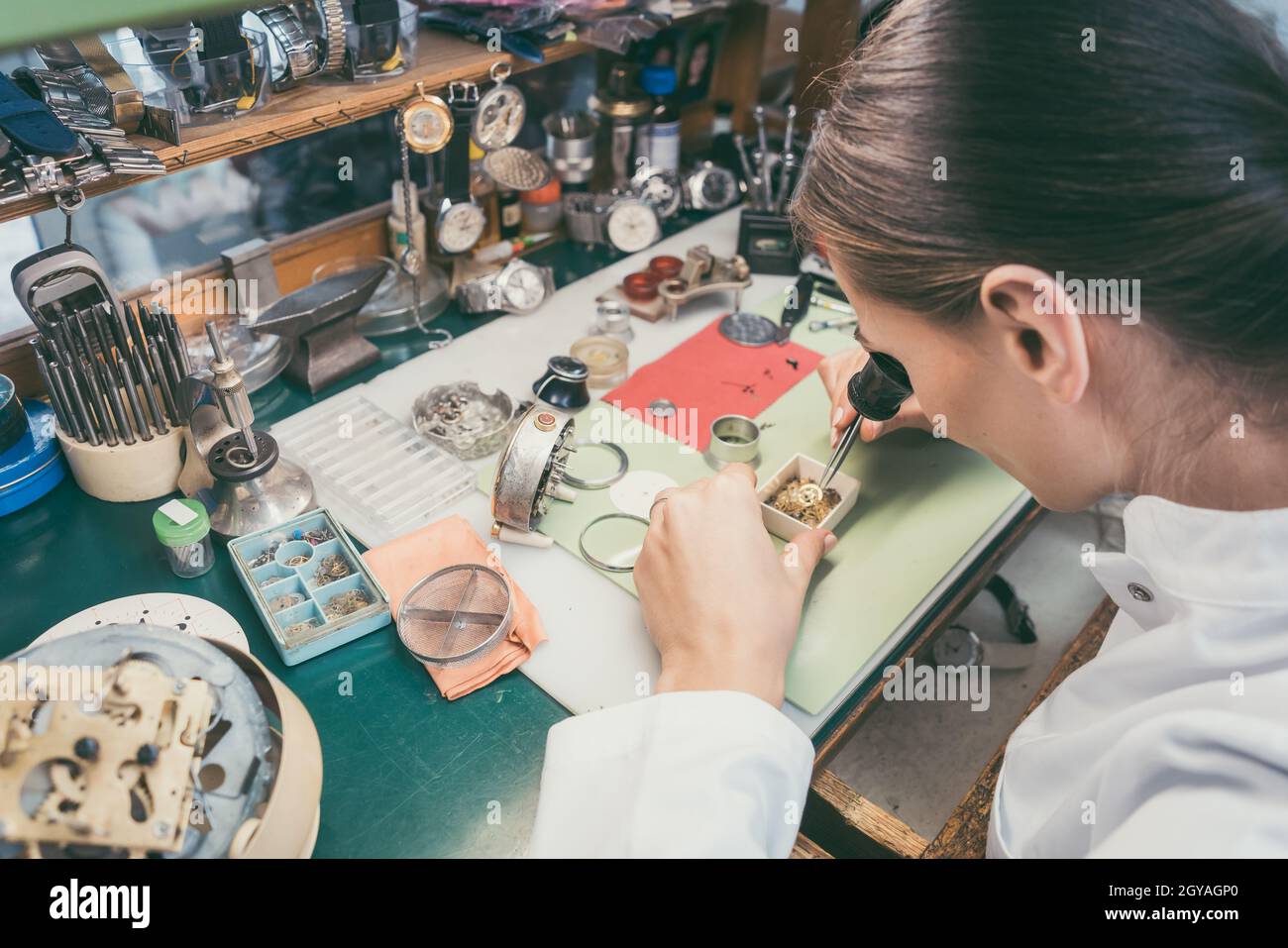 Donna orologiera assorbita nel suo delicato lavoro indossando occhiali Foto Stock