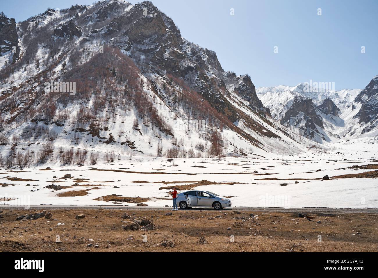 Il ragazzo lancia un quadricottero per sparare una strada di montagna serpentina. Tiro amatoriale della natura da un'altezza. Viaggiare in Georgia. Foto Stock