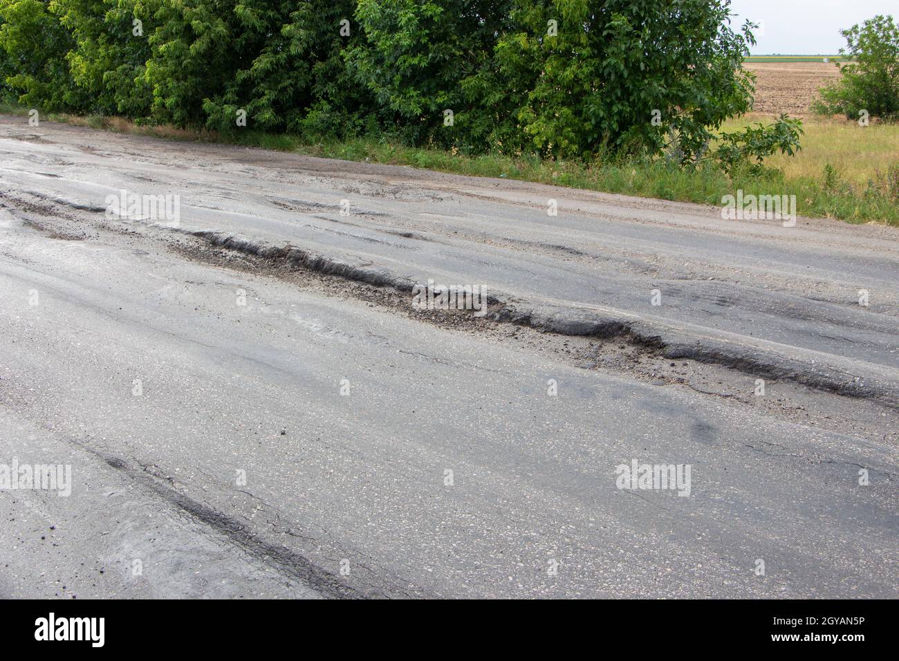 La strada è danneggiata, l'asfalto è rotto da camion. Foto Stock