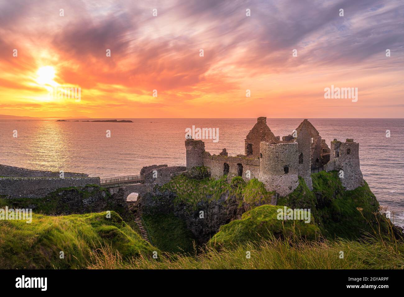 Tramonto sulle rovine del castello di Dunluce situato sul bordo della scogliera, Bushmills, Irlanda del Nord. Location di film del popolare spettacolo televisivo Game of Thrones Foto Stock