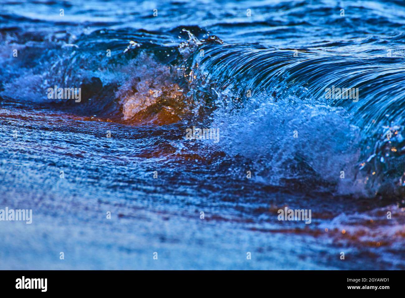 Un'onda instabile si rompe durante una tempesta di blues e violetti profondi Foto Stock