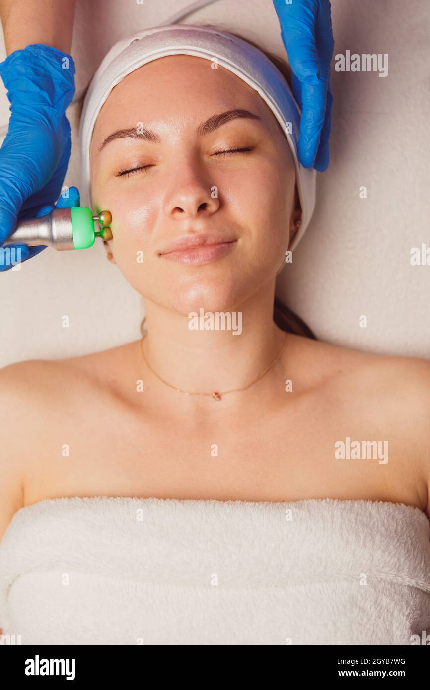 Giovane donna che ottiene microcorrenti pulizia della pelle e trattamento viso al salone di bellezza. Foto Stock