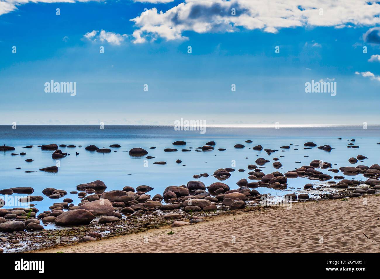 Rocce di pietra di sabbia Seape con acqua calma contro Blue Skies. Foto Stock