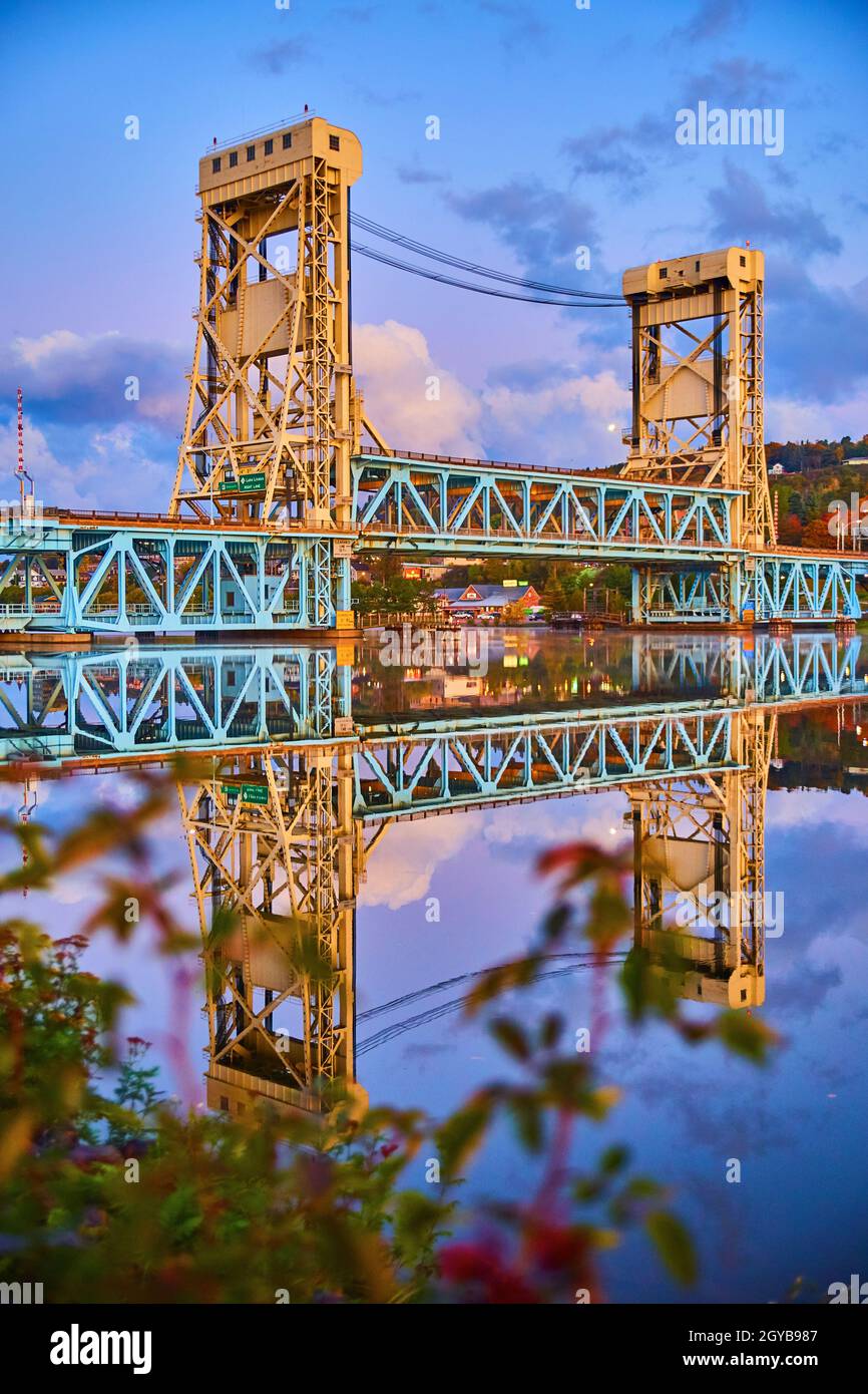 L'alba di Houghton di blu e purple molli e il ponte dell'ascensore si riflette in specchio come il fiume di acqua e una pianta sfocata nelle vicinanze Foto Stock