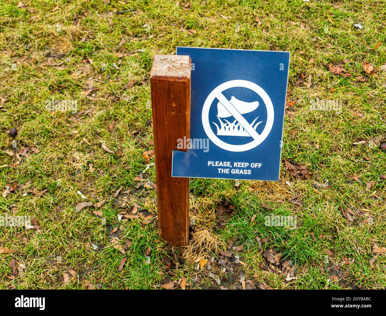 Un cartello per non camminare sul prato che avverte delle regole di condotta in un parco pubblico. Immagine di sfondo. Un luogo. Per il testo. Scarpe da ginnastica sportive. Foto Stock