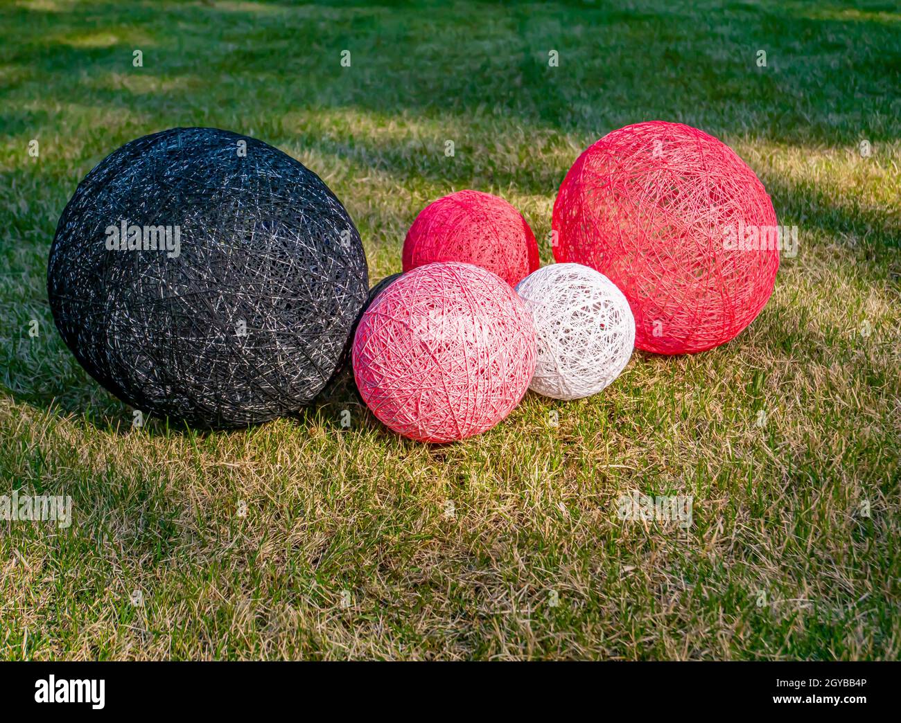 Palline colorate di filo avvolto su un prato erboso. Design. Immagine di sfondo. Posiziona per testo. Interno. Foto Stock