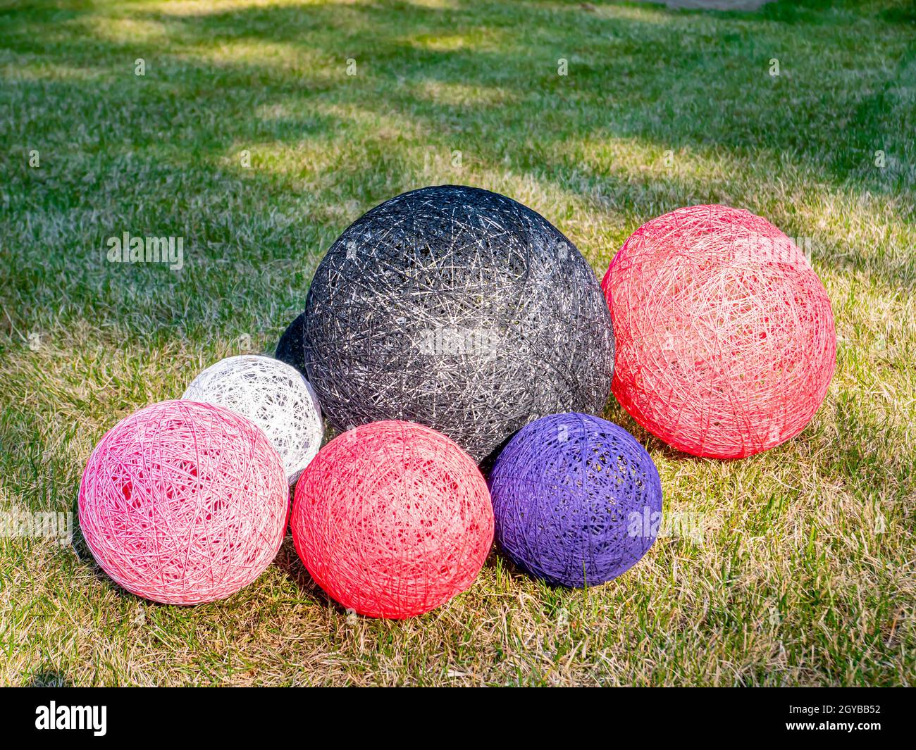 Palline colorate di filo avvolto su un prato erboso. Design. Immagine di sfondo. Posiziona per testo. Interno. Foto Stock