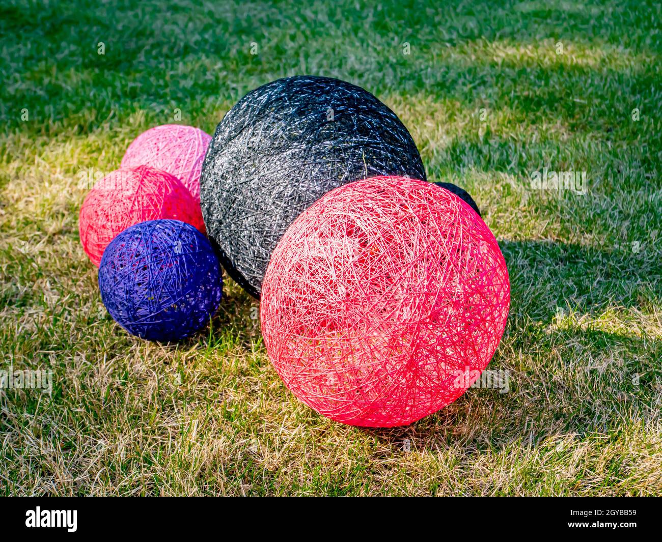 Palline colorate di filo avvolto su un prato erboso. Design. Immagine di sfondo. Posiziona per testo. Interno. Foto Stock