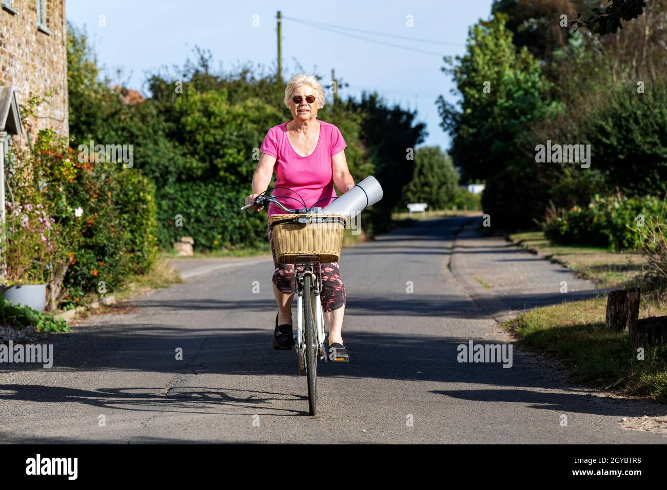 Donna anziana in bicicletta per la sua classe yoga Foto Stock