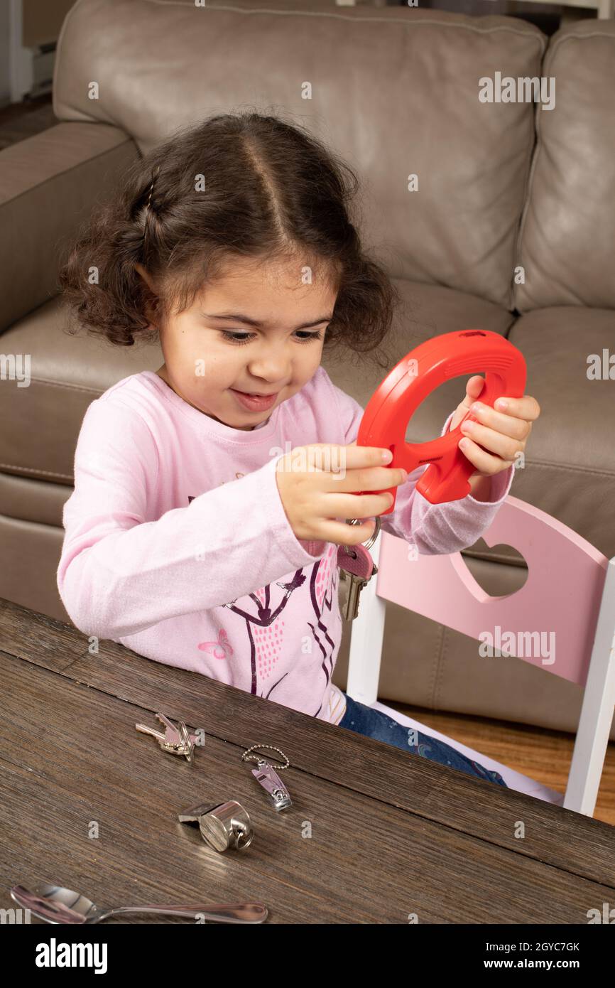 Ragazza di tre anni che gioca con oggetti magnetici e metallici Foto Stock