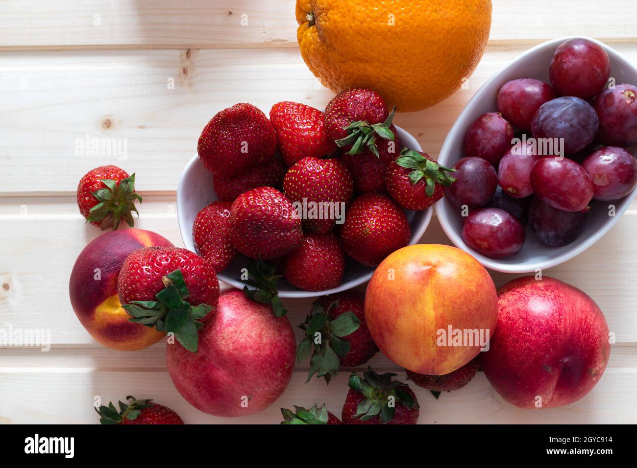 Benefici per la salute e la vita di fragole, uva, nettarine, arance; foto ad alto angolo di frutta su sfondo tradizionale in legno Foto Stock