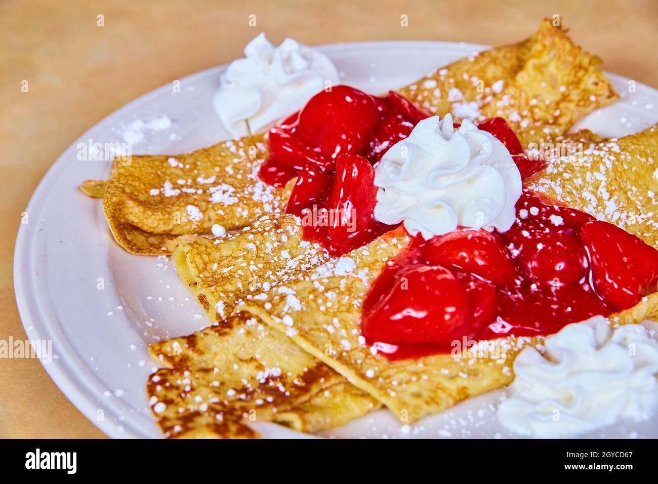 Deliziose crepes francesi tradizionali condite con fragole sciroppate, zucchero in polvere e panna montata Foto Stock