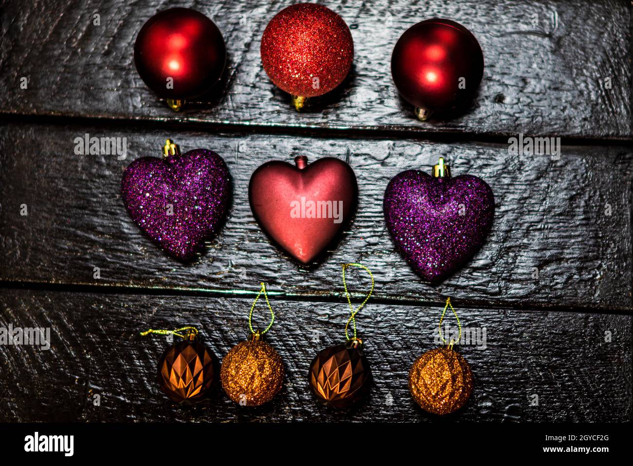 Primo piano di giocattoli colorati di Natale di diverse forme su una superficie di legno nero Foto Stock