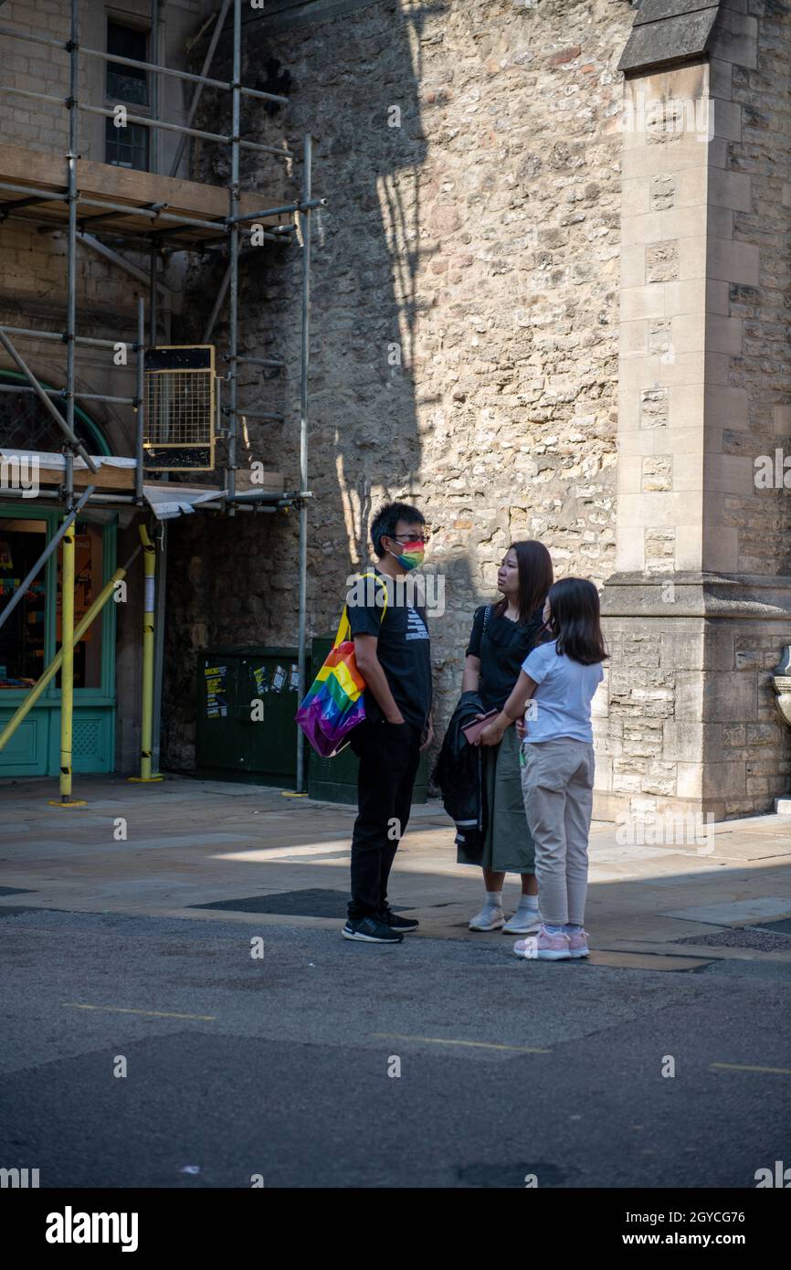 I turisti si riuncono in strada a Oxford sotto la Torre Carfax Foto Stock