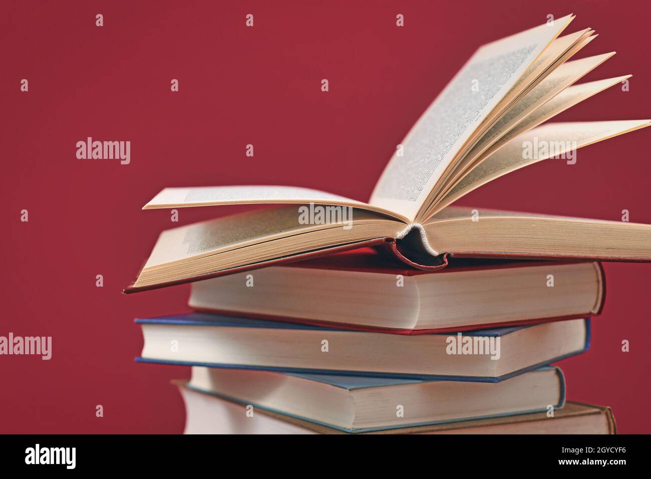 Pila di vecchi libri di copertina rigida su sfondo rosso scuro Foto Stock