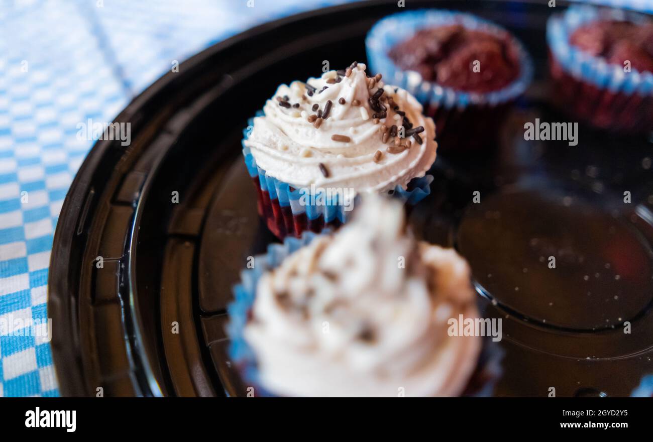 Due tortini e due muffin su un vassoio di plastica nero rotondo Foto Stock