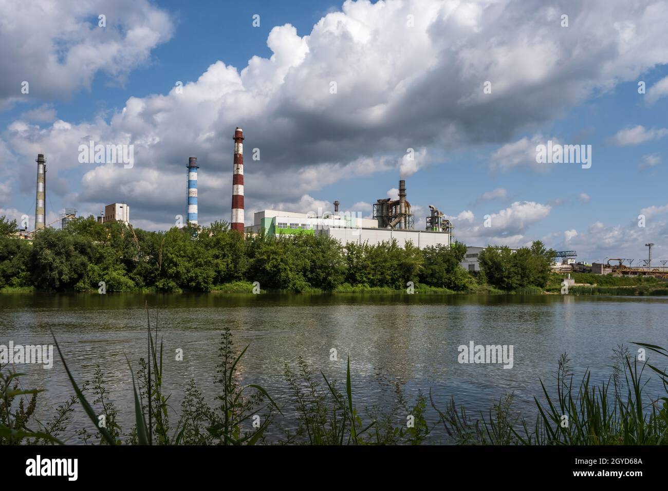 tubi di legno impresa segheria pianta vicino fiume. Concetto di inquinamento dell'aria. Paesaggio industriale inquinamento ambientale spreco di energia termica p Foto Stock
