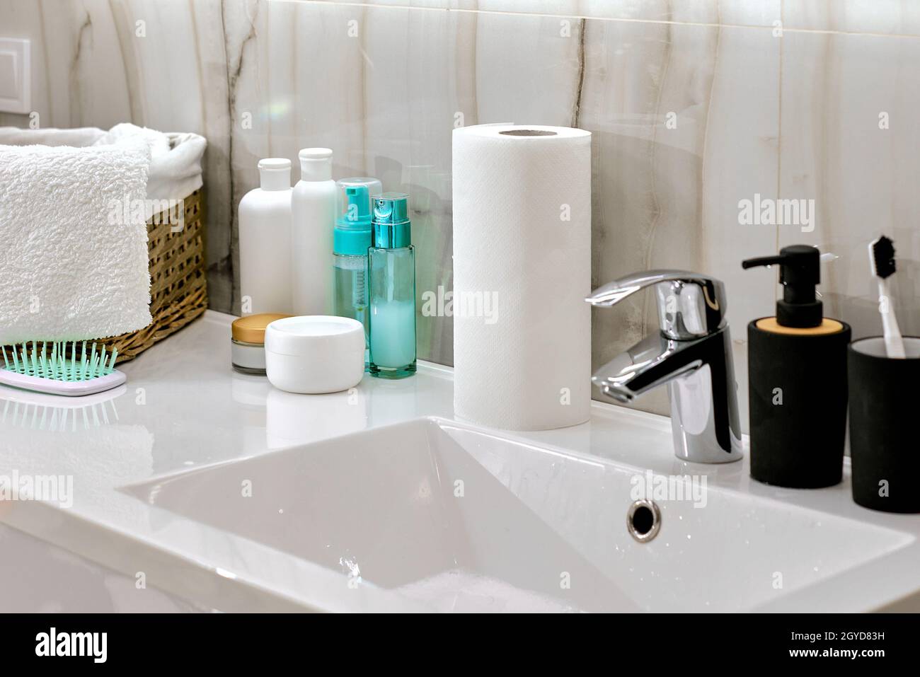 Interno del bagno con lavabo, rubinetto e bottiglie di cosmetici Foto Stock