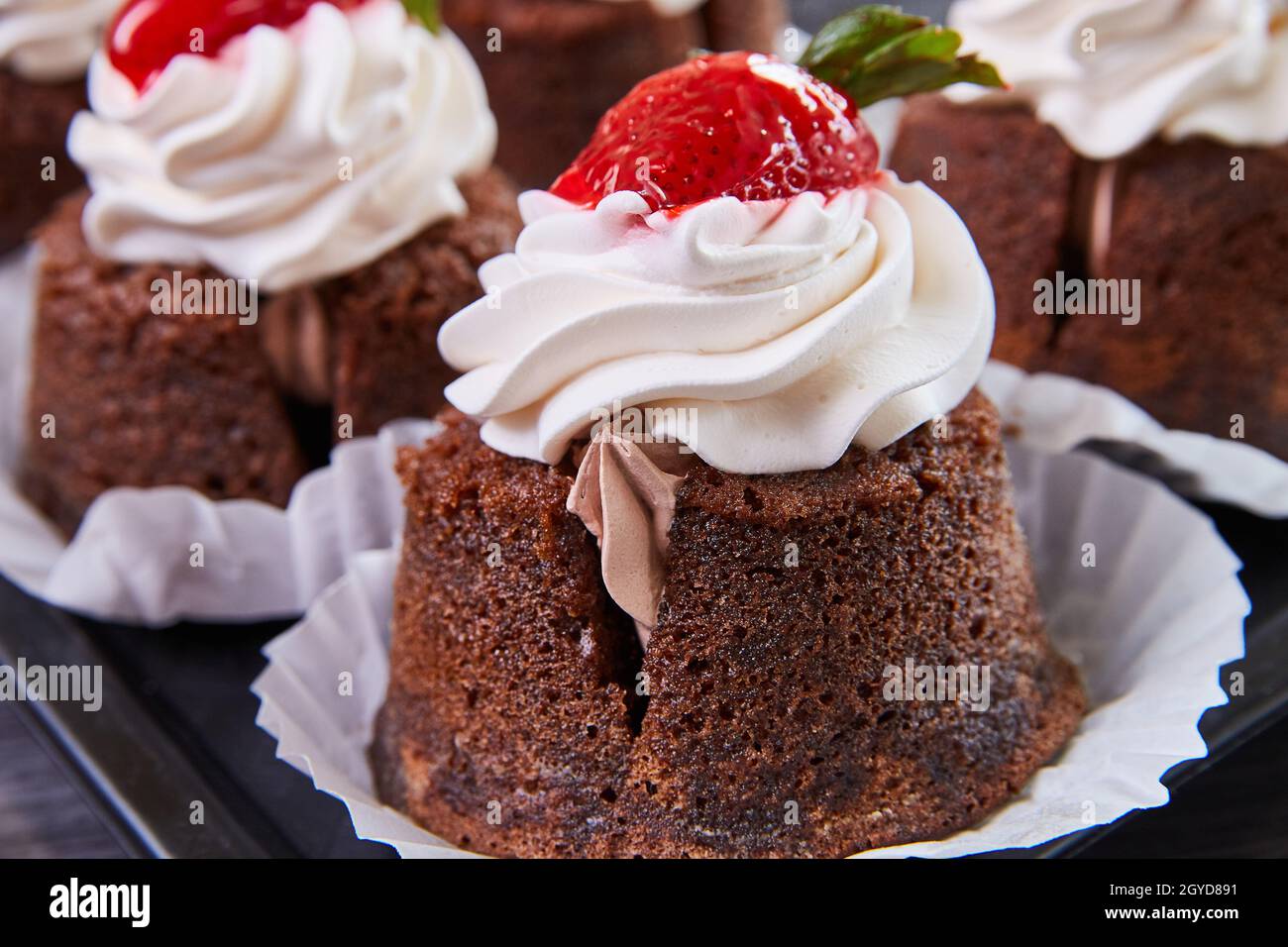 Dettaglio di un delizioso cupcake da forno ripieno di glassa e condito con ciliegia Foto Stock