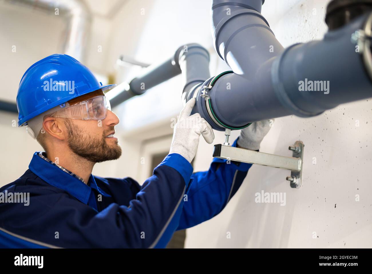 Ispezione del tubo dell'acqua in PVC da parte del lavoratore edile Foto Stock