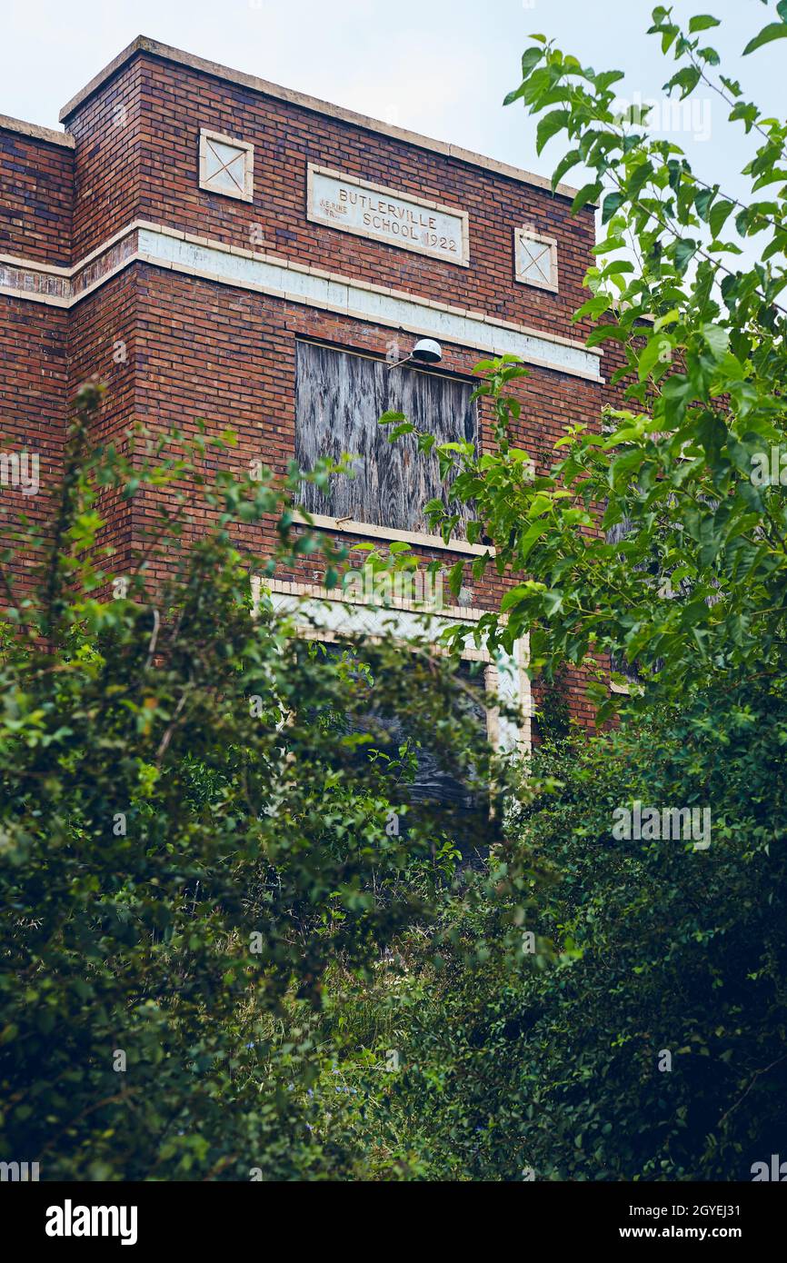 Edificio in mattoni rossi abbandonato della scuola superiore circondato da cespugli verdi Foto Stock