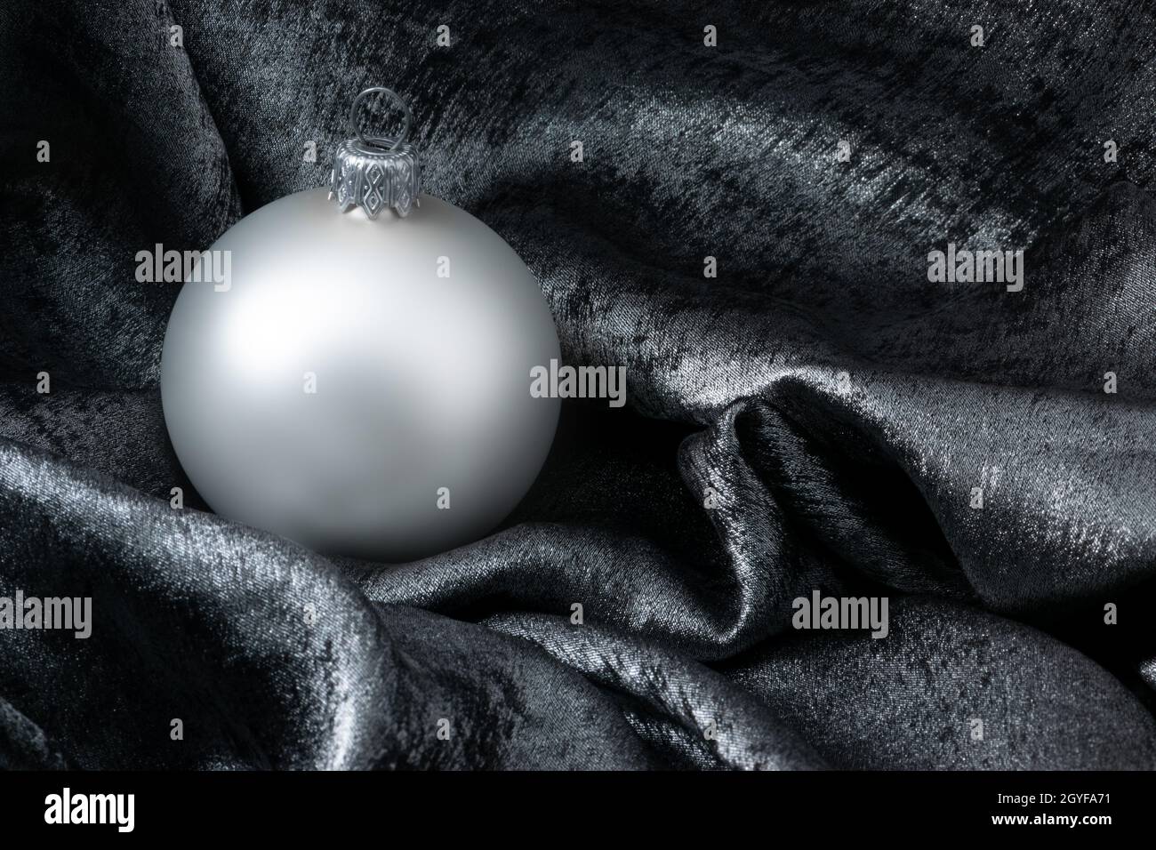 Decorazione bauble di Natale su sfondo argento con spazio copia per il testo. Biglietto di auguri per l'anno nuovo. Carta di Natale lucida con sfera di Natale su argento Foto Stock