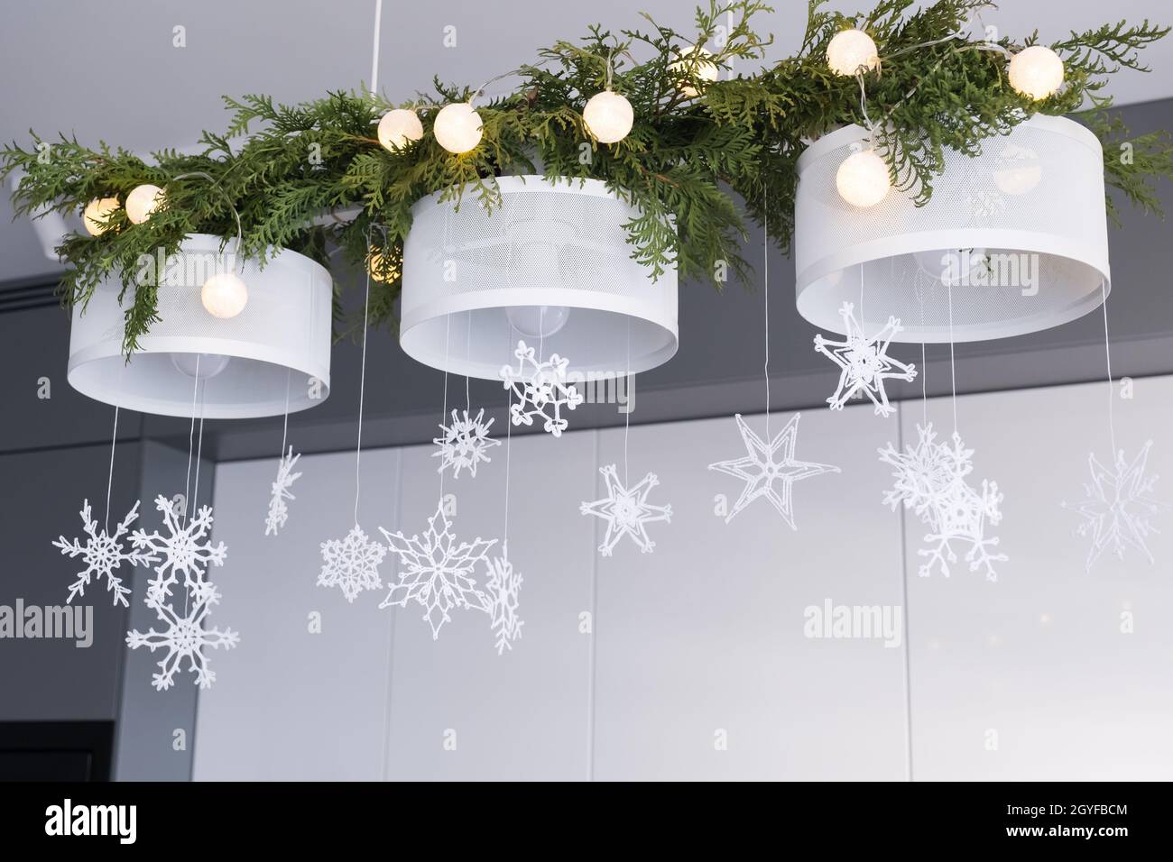 Decorazioni per interni di Natale. Delicati fiocchi di neve in maglia  bianca, rami di abete e luci natalizie su un lampadario. Messa a fuoco  selettiva Foto stock - Alamy