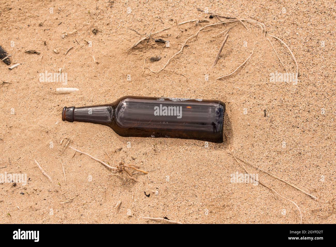 Qualcuno ha lasciato una bottiglia vuota sulla sabbia invece di riciclarla. Foto Stock