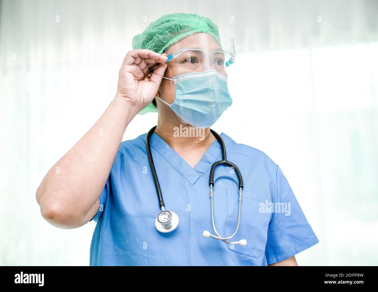 Medico asiatico che indossa maschera, visiera e DPI tuta nuova normale isolato su sfondo bianco con percorso di ritaglio per proteggere l'infezione di sicurezza Covid-19 Co Foto Stock