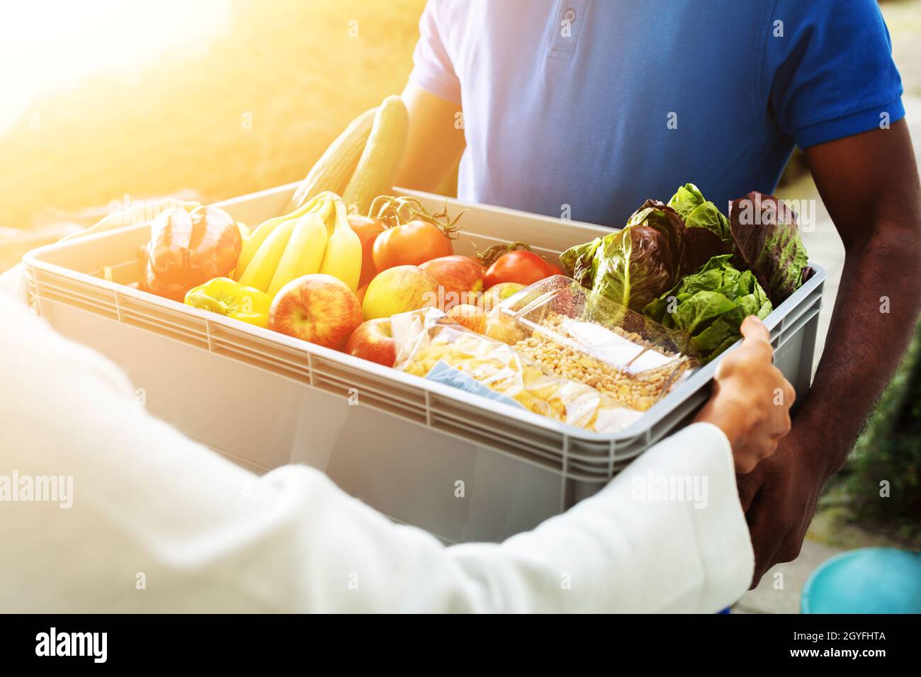 African Man Grocery Delivery. Donna che prende Crata vegetale Foto Stock