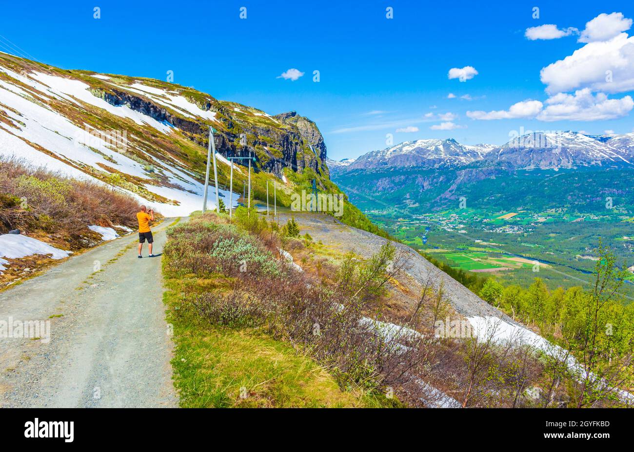 Turista su sentiero da una bella valle paesaggio panorama Norvegia di Hemsedal Hydalen con nevicate in montagna in estate. Foto Stock