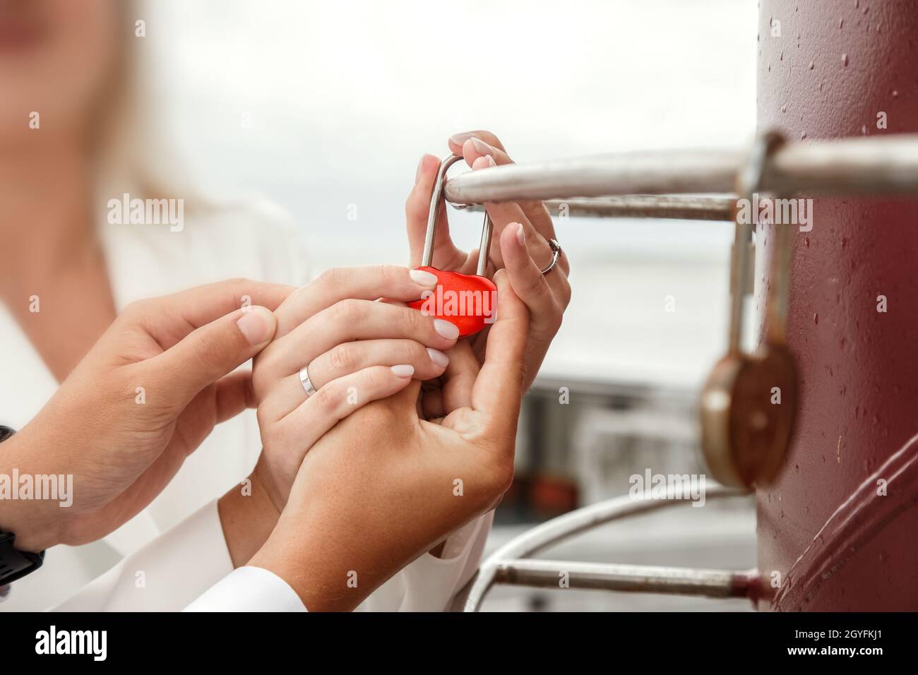 Gli sposi novelli appendono la serratura che simboleggia l'amore eterno il giorno di nozze. Tradizione di nozze. Foto Stock