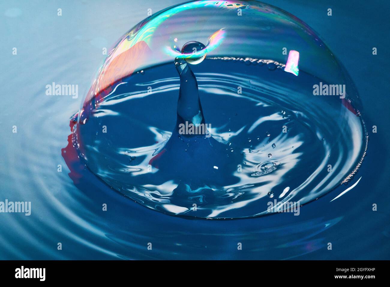 La superficie blu e la bolla come goccia di acqua quasi si rompe in bolla per collidere con un altro flusso di acqua Foto Stock
