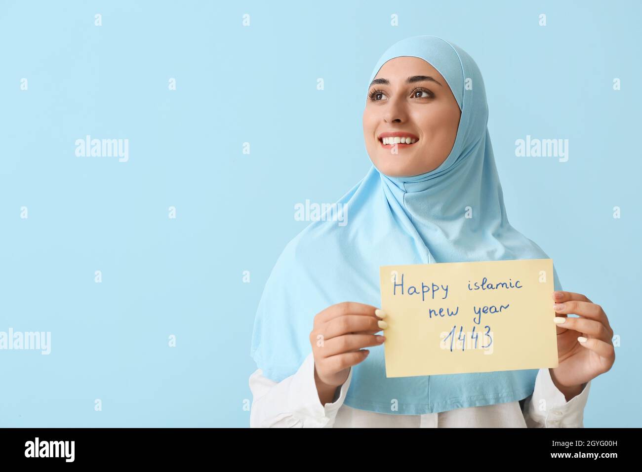 Giovane musulmana con biglietto di auguri per il nuovo anno Islamico su sfondo a colori Foto Stock