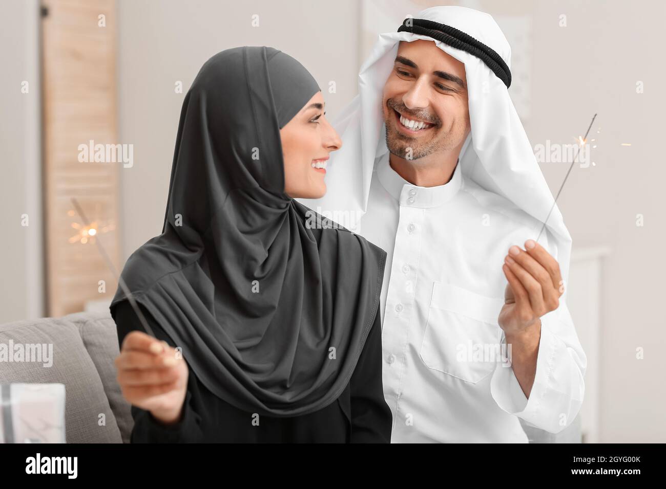 Giovane coppia musulmana con scintillanti a casa Foto Stock
