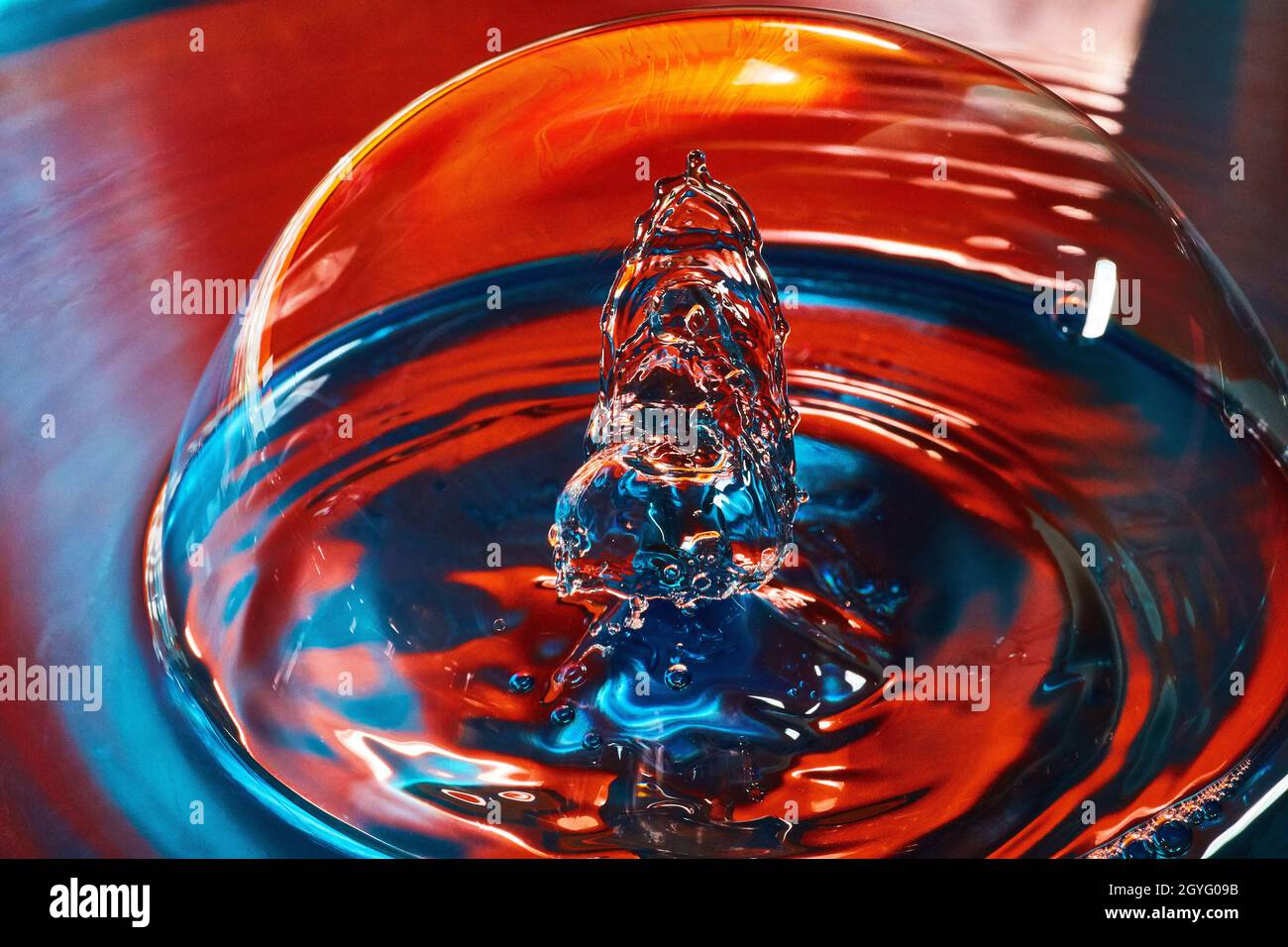 Acqua blu e rossa con bolla grande e due gocce d'acqua che si scontrano all'interno Foto Stock