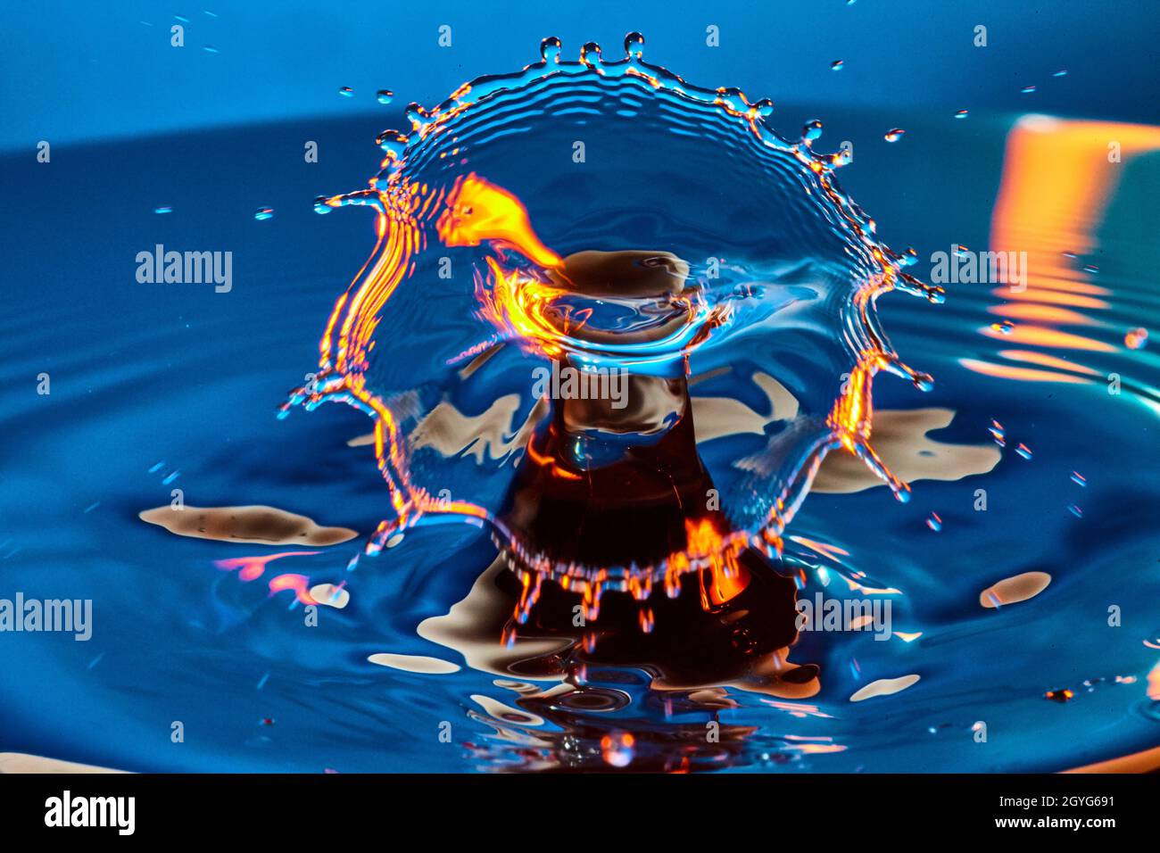 Spruzzi di blu con una goccia d'acqua arancione brillante Foto Stock