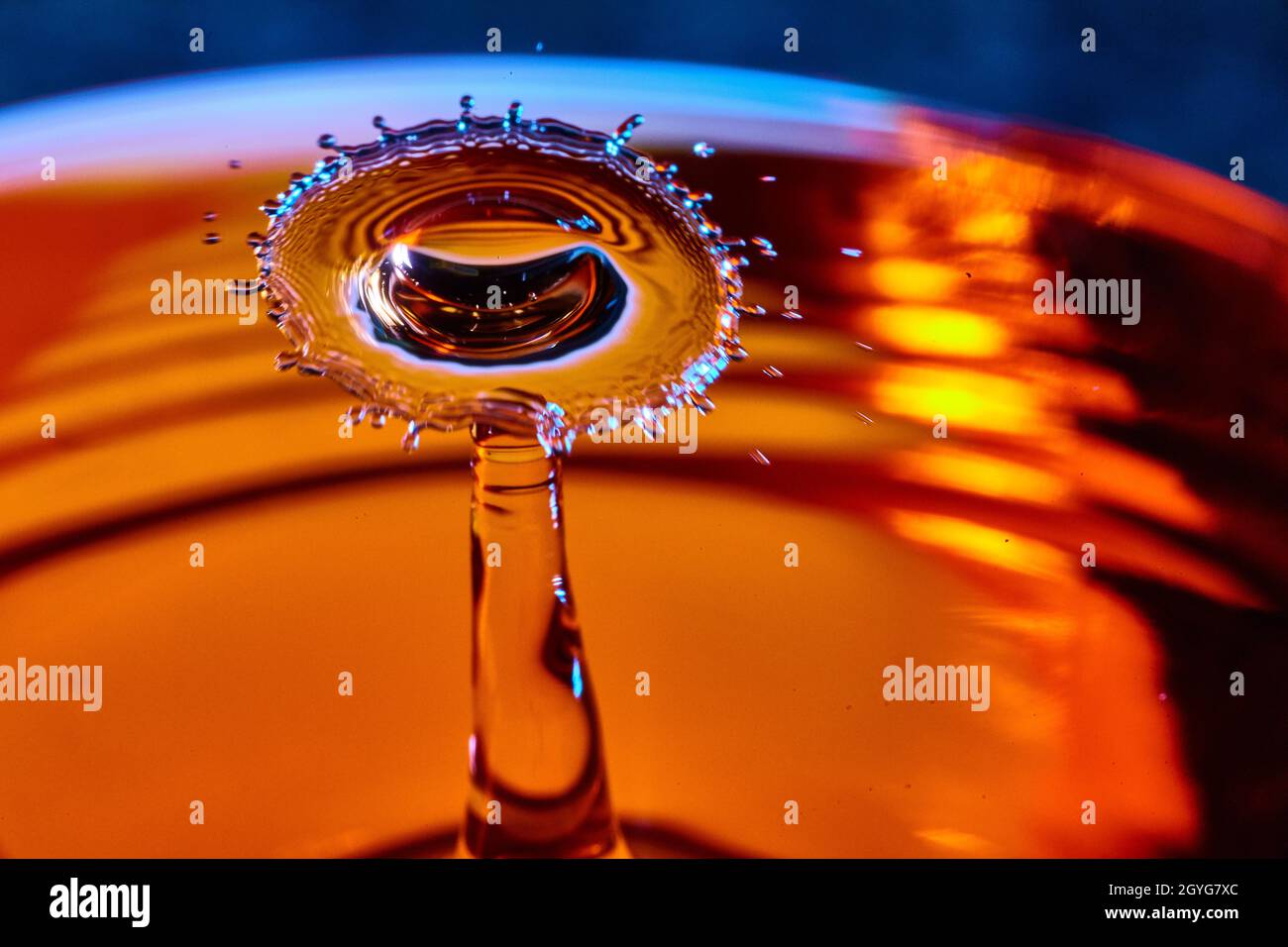 Gocce d'acqua splash in una tazza arancione di tè Foto Stock