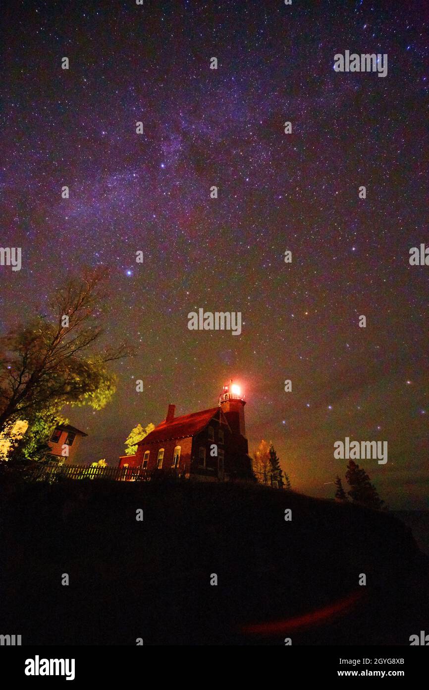 Via Lattea sopra il faro del porto con la luce accesa Foto Stock