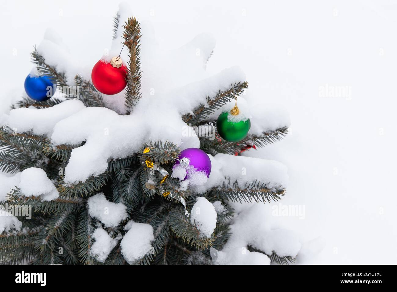 Piccolo albero di Natale con palline colorate decorazione coperto di neve Foto Stock
