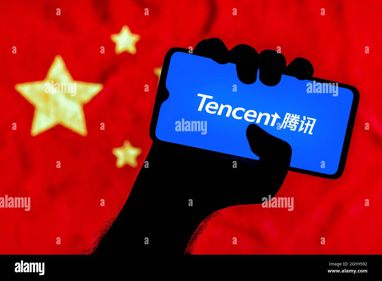 Uno smartphone con il logo Tencent in una mano applaiata. Foto Stock
