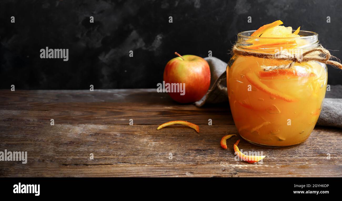 Marmellata di mele in un vaso di vetro trasparente. Marmellata di mele e arancio su uno sfondo chiaro. Deliziosa marmellata. Foto Stock