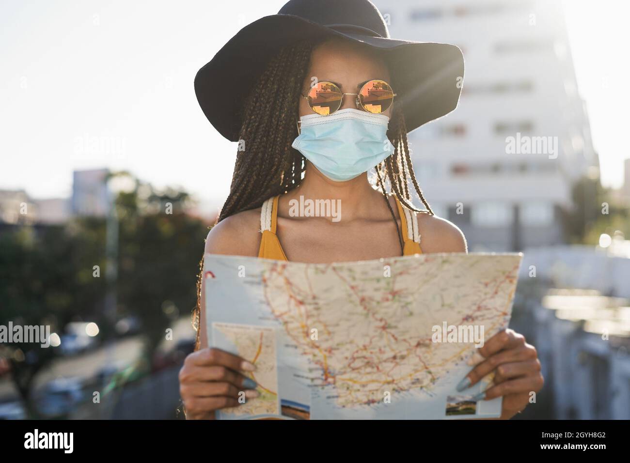 Giovane ragazza turistica hipster utilizzando mappa all'aperto, mentre indossa la maschera di sicurezza in vacanza di viaggio - Focus sul viso Foto Stock