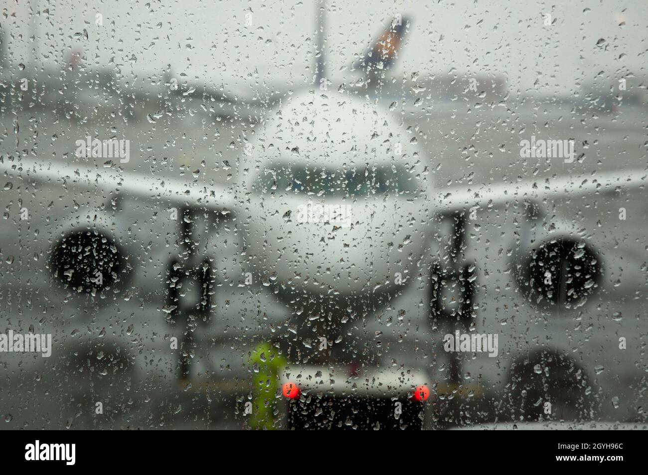 Aeroplano sulla pista visto attraverso la finestra bagnata il giorno piovoso - fuoco sulle gocce dell'acqua sulla finestra Foto Stock