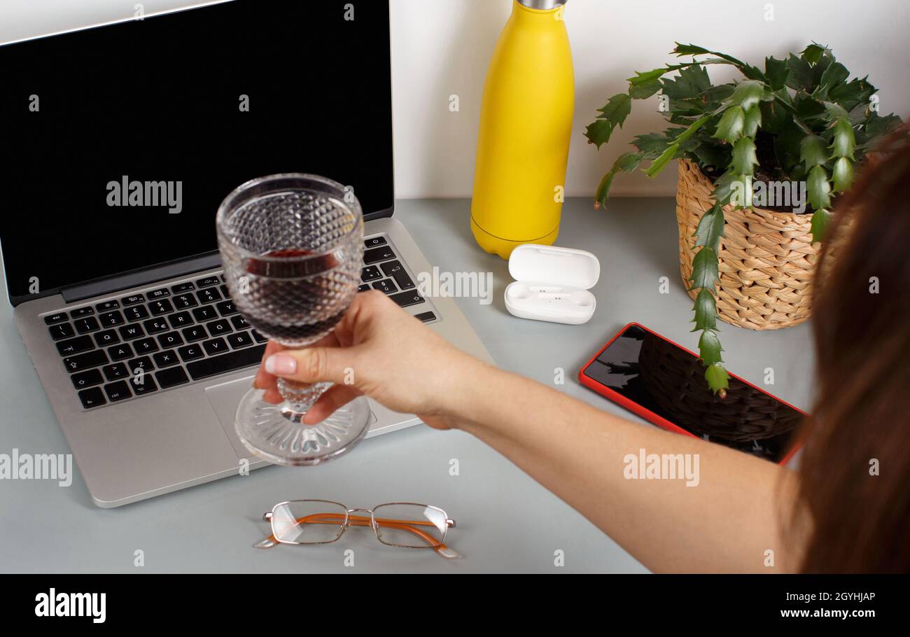 Brindisi donna con un computer portatile e un bicchiere di vino rosso. Due  amici che hanno una videochiamata su un portatile a casa, primo piano Foto  stock - Alamy