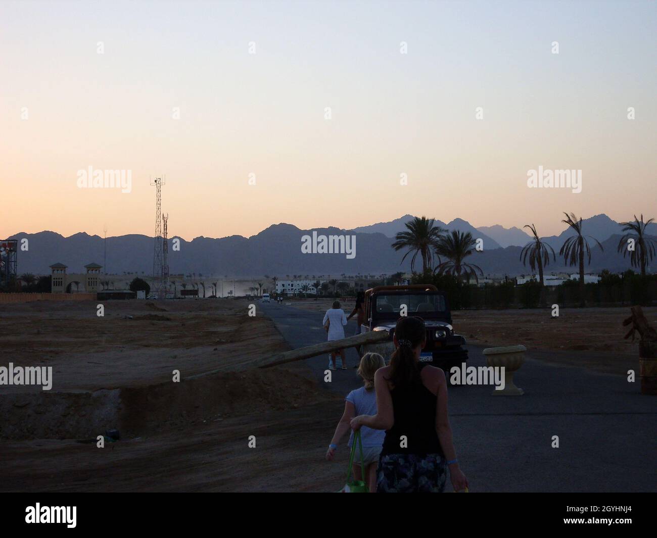 La gente cammina sullo sfondo del tramonto e delle montagne nella località araba Foto Stock