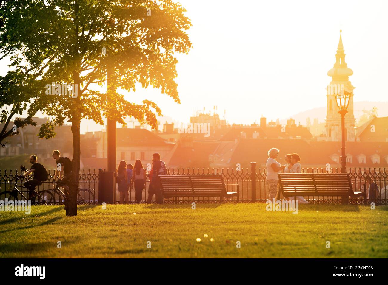 Persone che camminano nel parco cittadino illuminato dal sole a Budapest Foto Stock