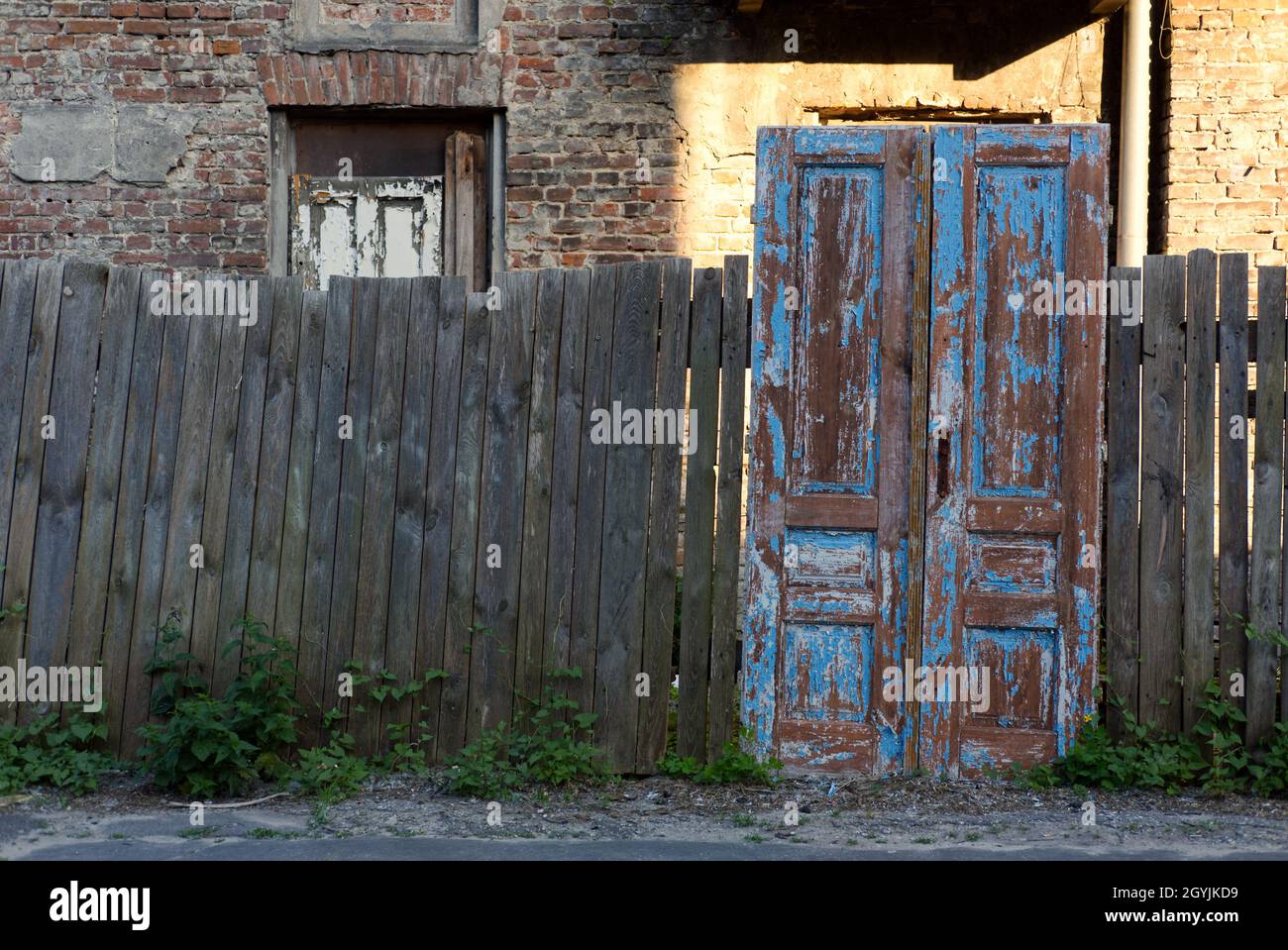 vecchia recinzione di legno accovacciata e porta intemperata che conduce a nessun posto Foto Stock