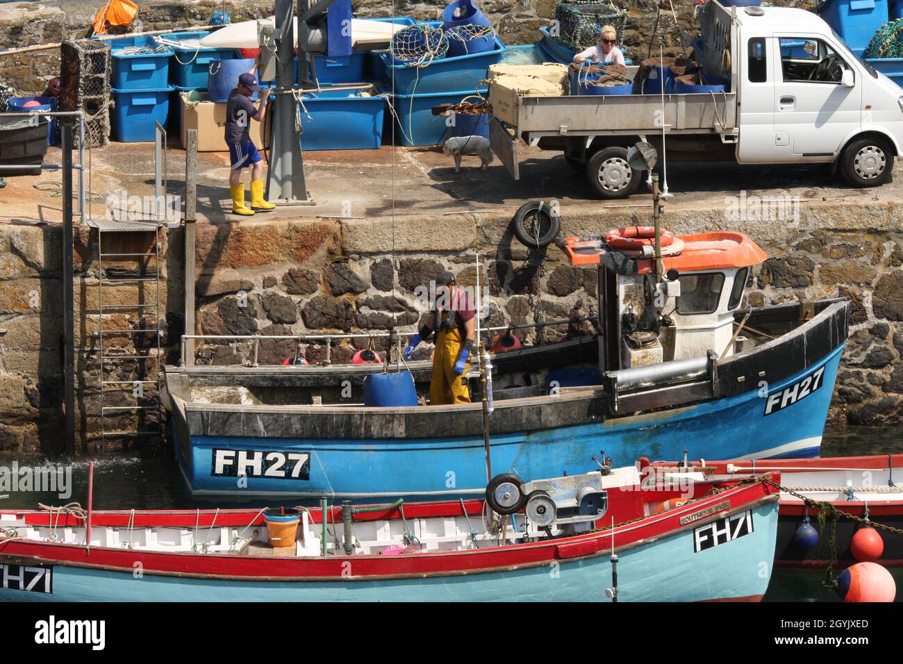 Fine della giornata di pesca per la piccola barca da pesca con la famiglia che aiuta a scaricare il pescato Foto Stock