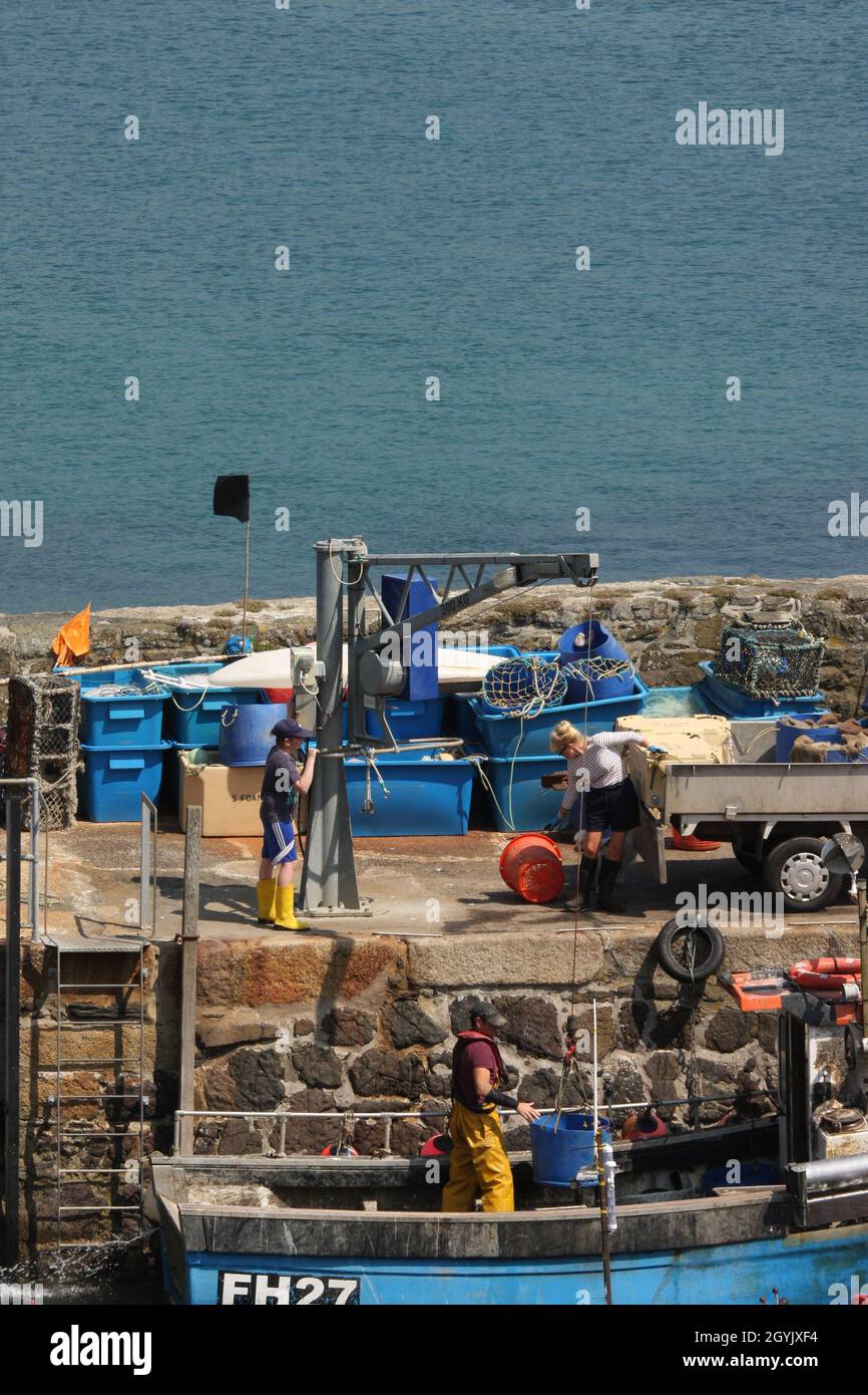 Fine della giornata di pesca per la piccola barca da pesca con la famiglia che aiuta a scaricare il pescato Foto Stock